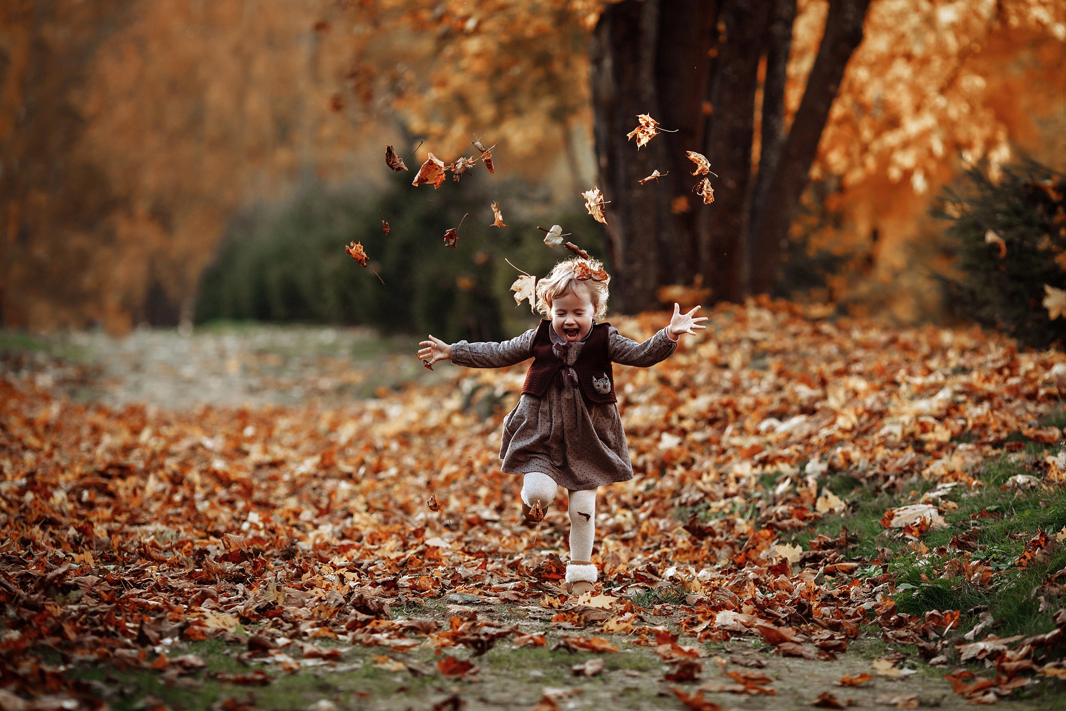 kid jumping into pile of leaves